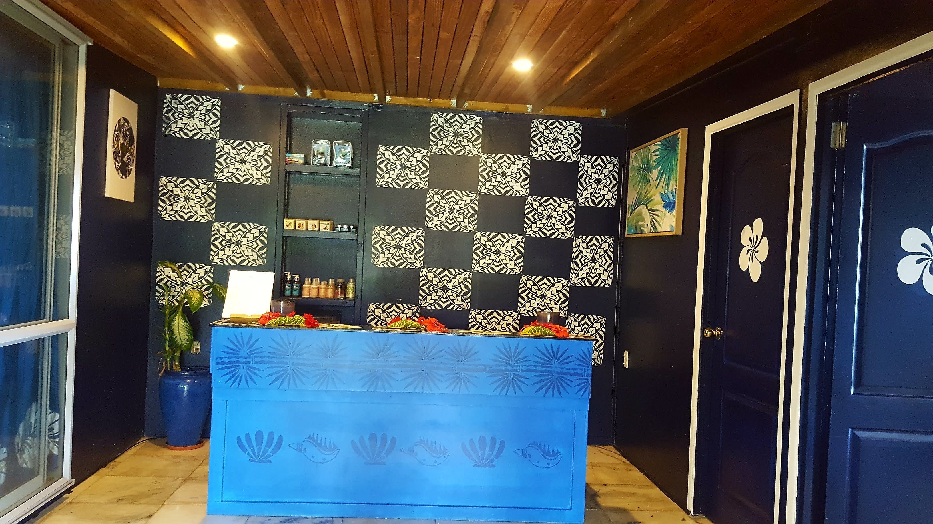 Un área de recepción con un mostrador azul, azulejos de pared estampados y una puerta con diseño floral.