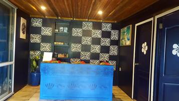 Un área de recepción con un mostrador azul, azulejos de pared estampados y una puerta con diseño floral.