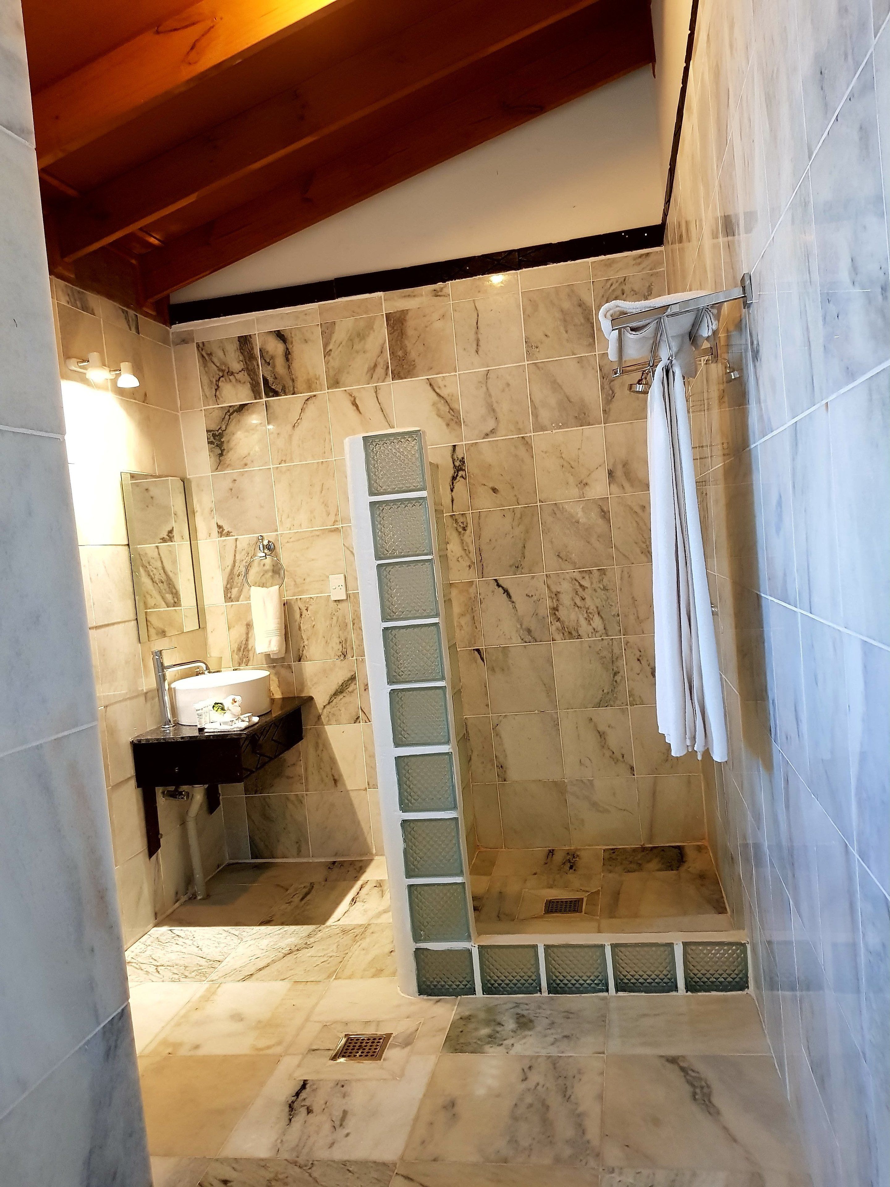 A bathroom with marble tiles, a sink, and a shower area.