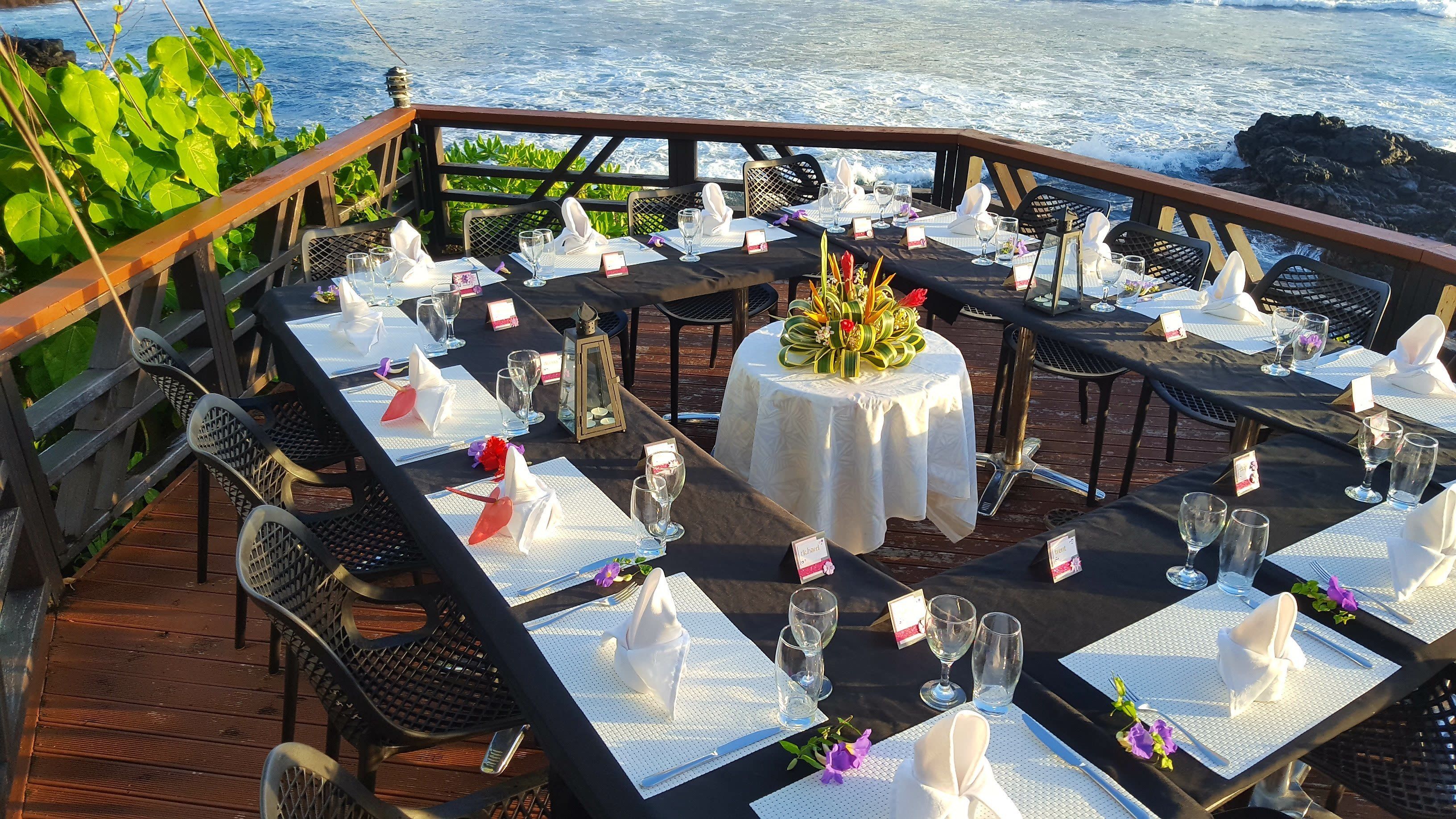 A dining area with tables set for a meal, overlooking the ocean.