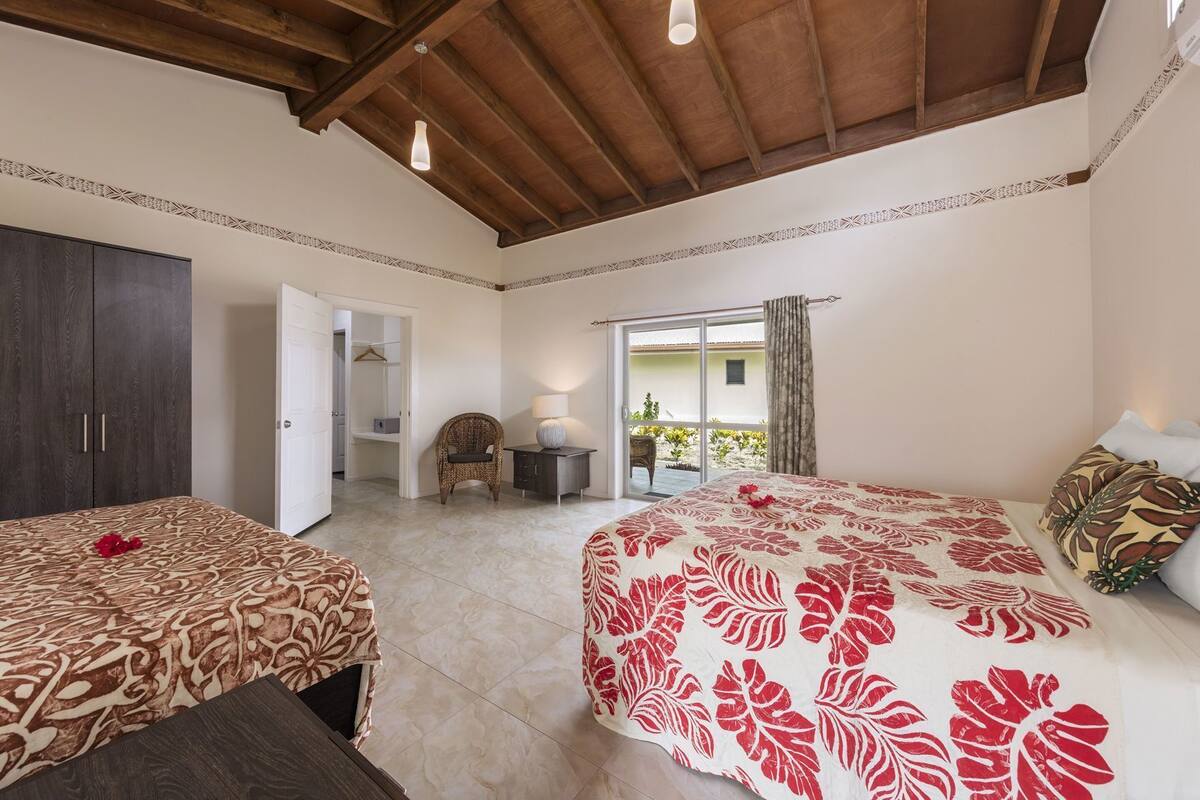Ein Schlafzimmer mit zwei Betten, einem Kleiderschrank, einem Sessel, einem kleinen Tisch und einem Balkon.