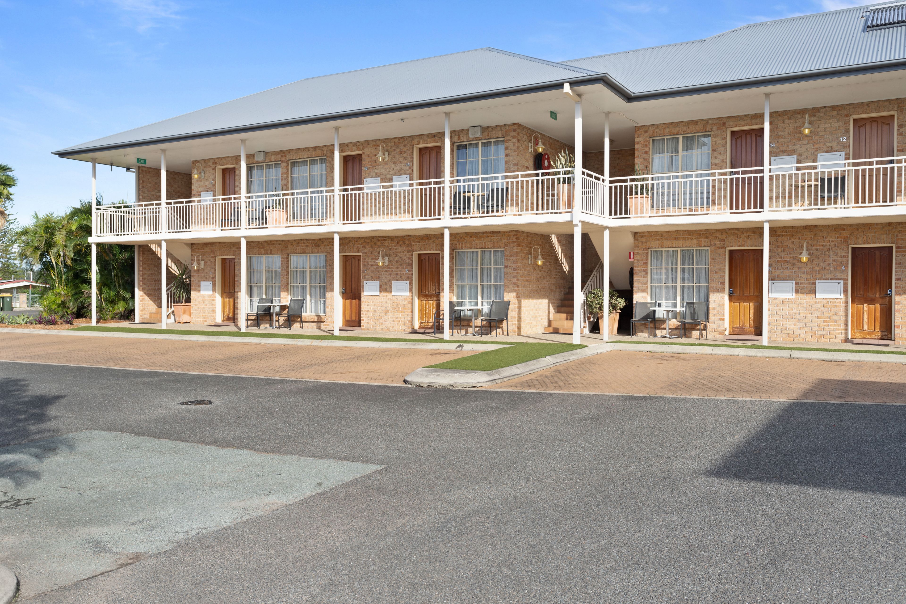 A two-story motel with a flat roof, multiple balconies, and a paved driveway.