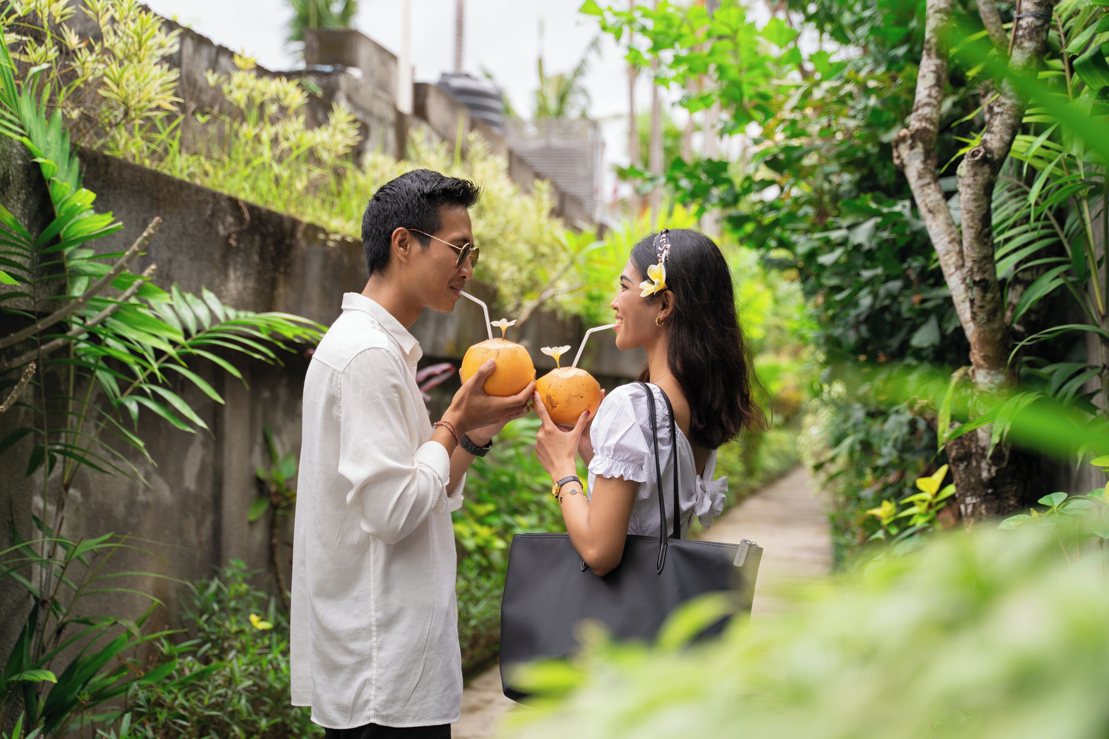 Una pareja sosteniendo cocos en un entorno exuberante y verde.