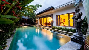 Una casa moderna con piscina, amplias ventanas y plantas tropicales.