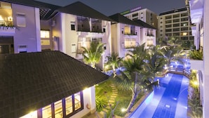 Un resort con varias edificaciones, una piscina y palmeras.