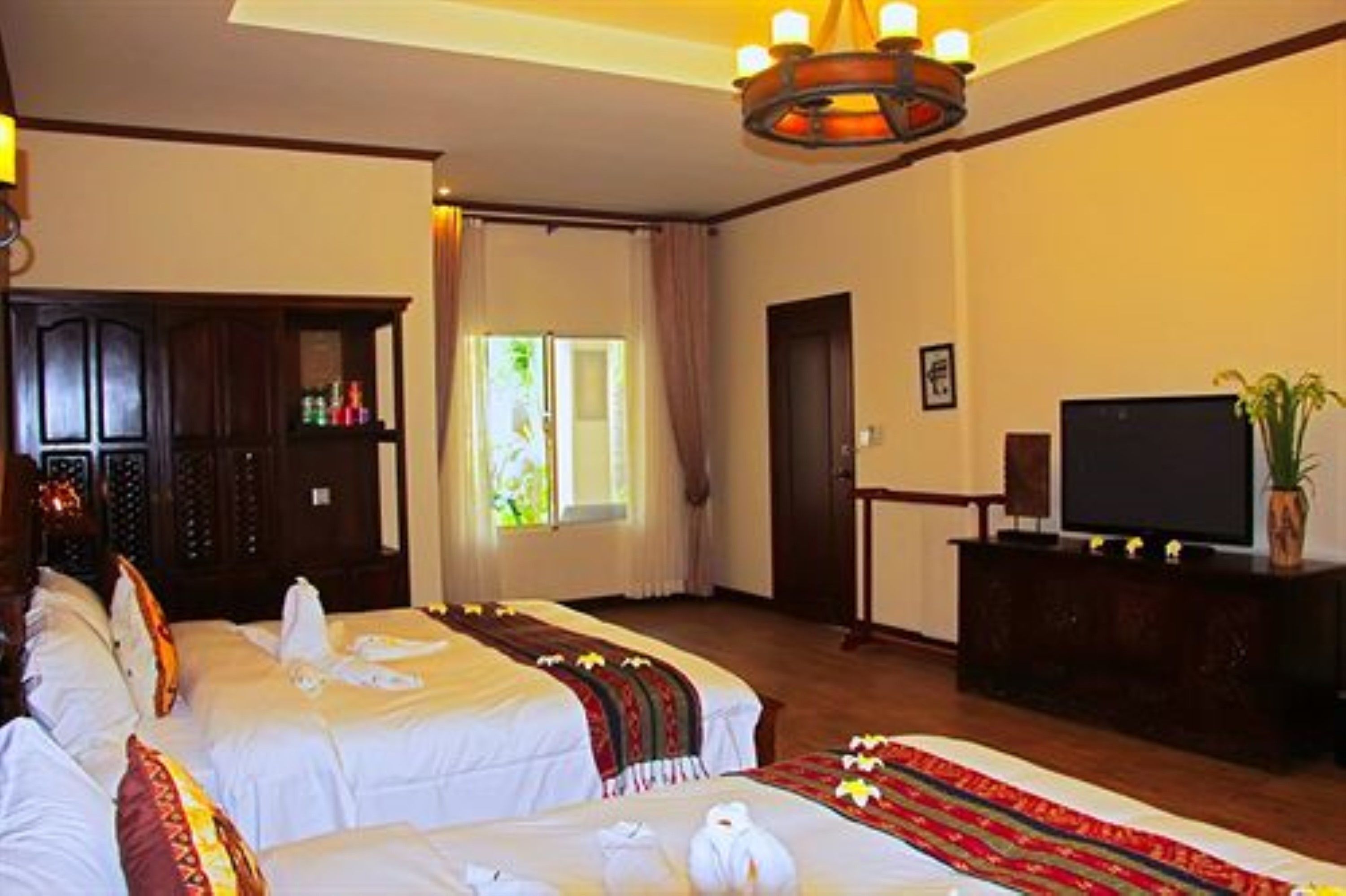 A hotel room with two beds, a television, and a cabinet.