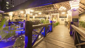 Un restaurante con un área exterior cubierta, una terraza de madera y una fuente de agua.