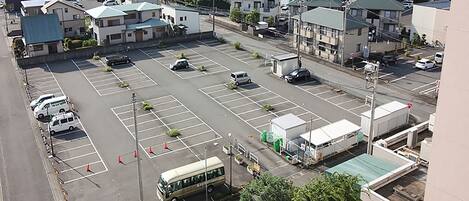 An aerial view of a parking lot with several cars and a bus, surrounded by industrial buildings and residential structures.