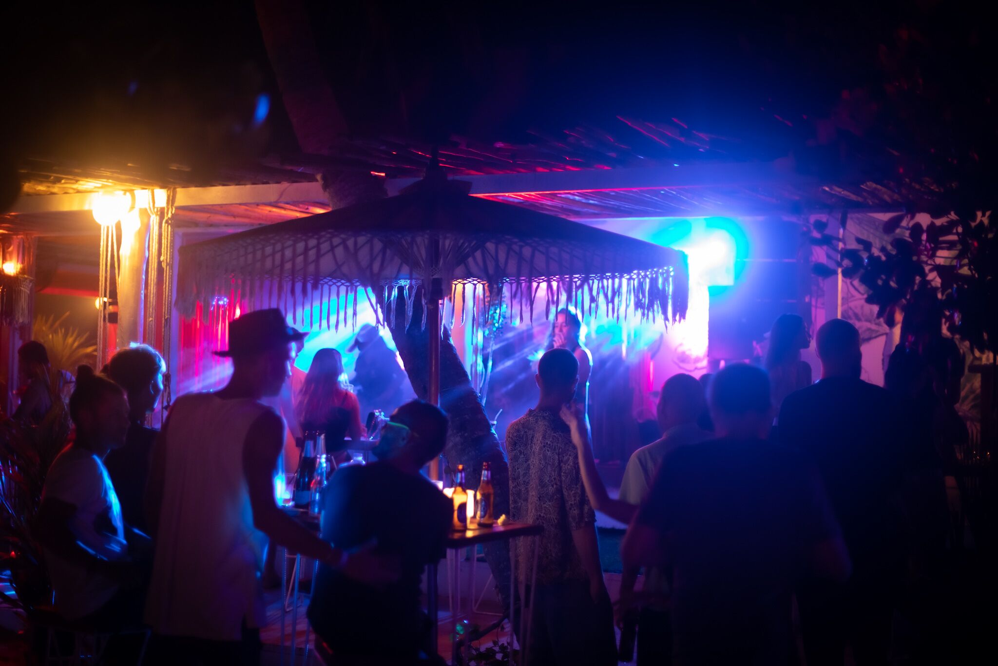 A crowded indoor venue with a central stage and a canopy structure.