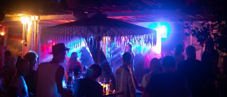 A crowded indoor venue with a central stage and a canopy structure.