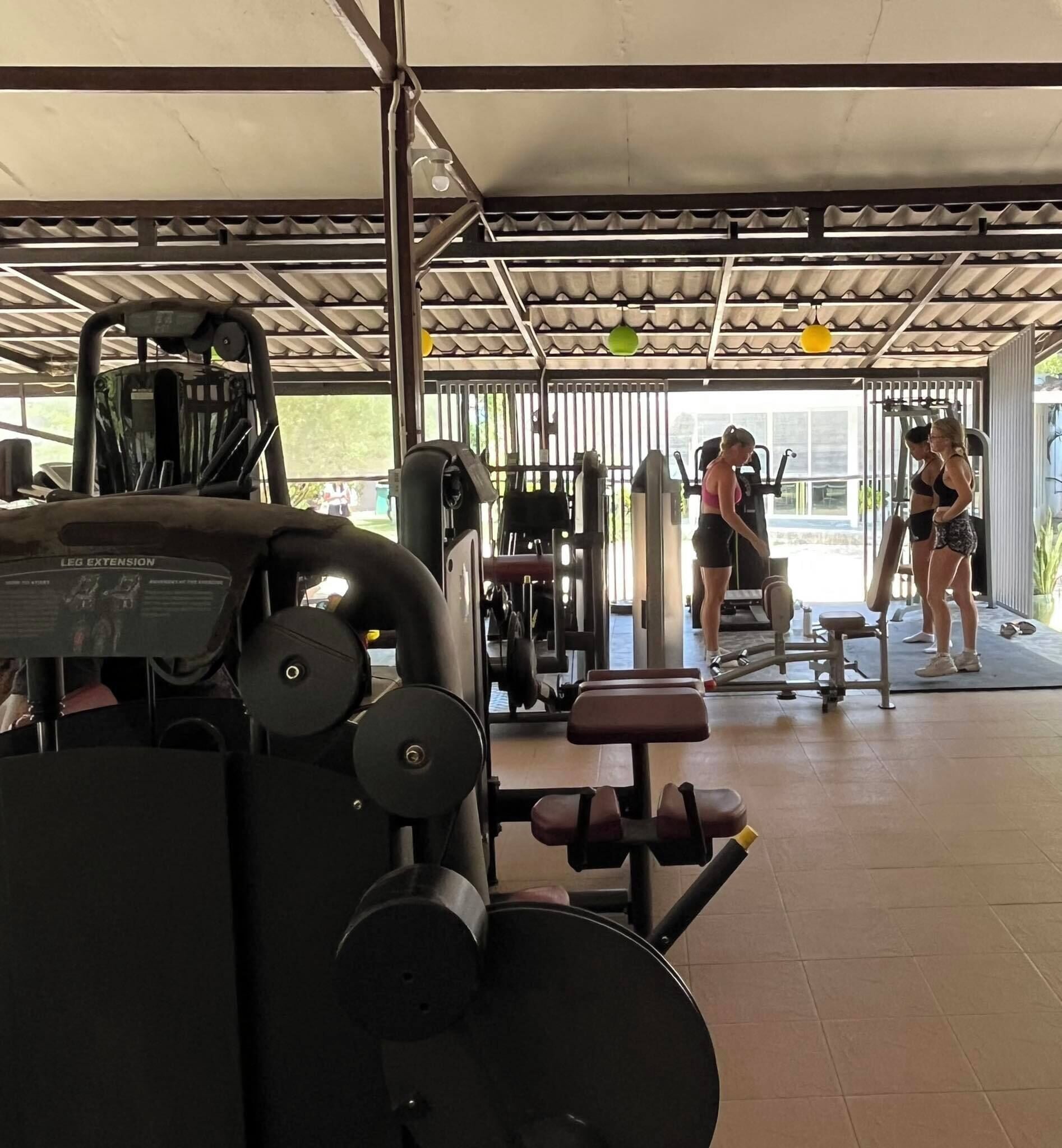 A gym with various exercise equipment, including a leg extension machine and dumbbells.