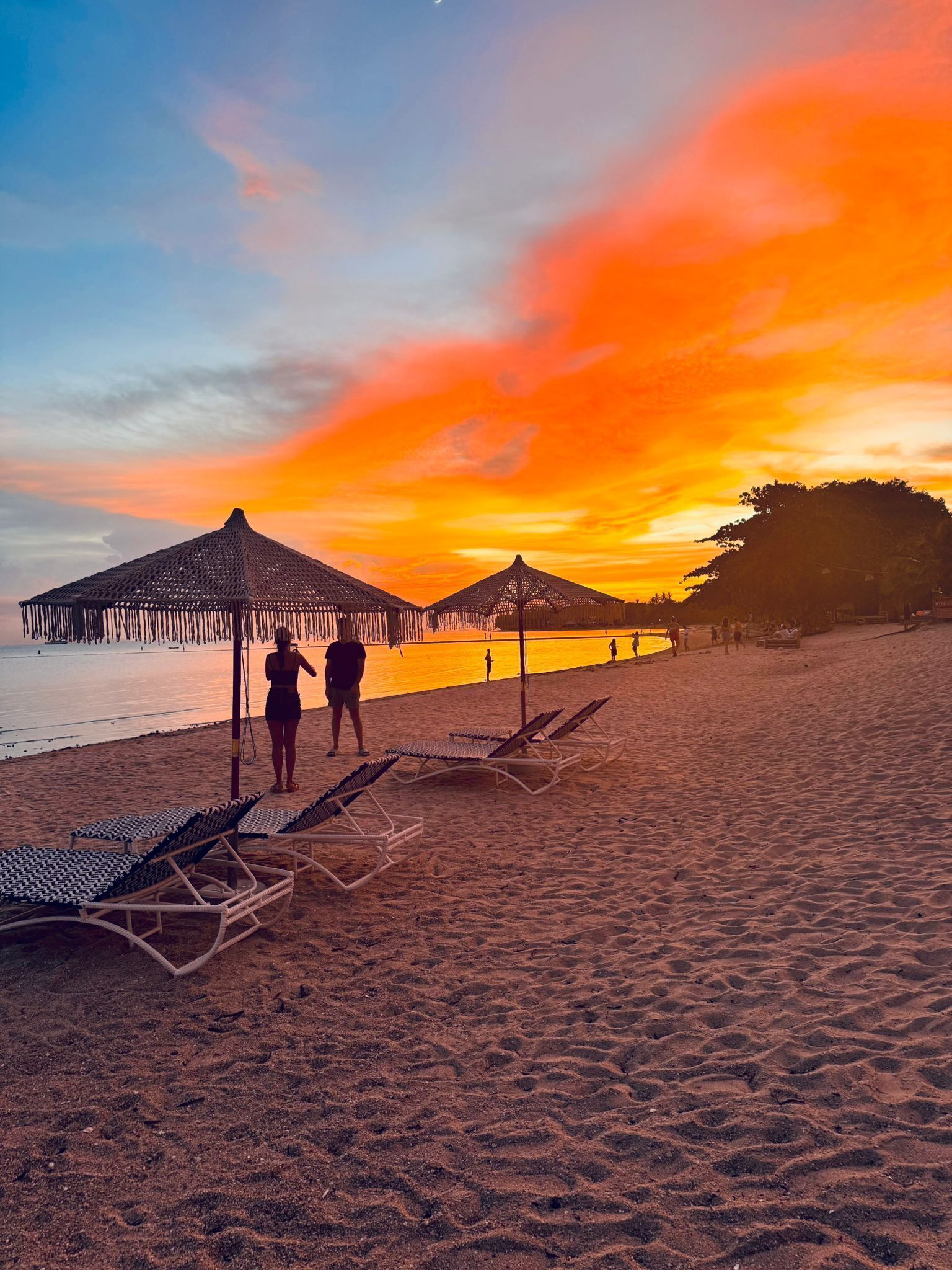 A beach with sun loungers and a thatched umbrella structure.