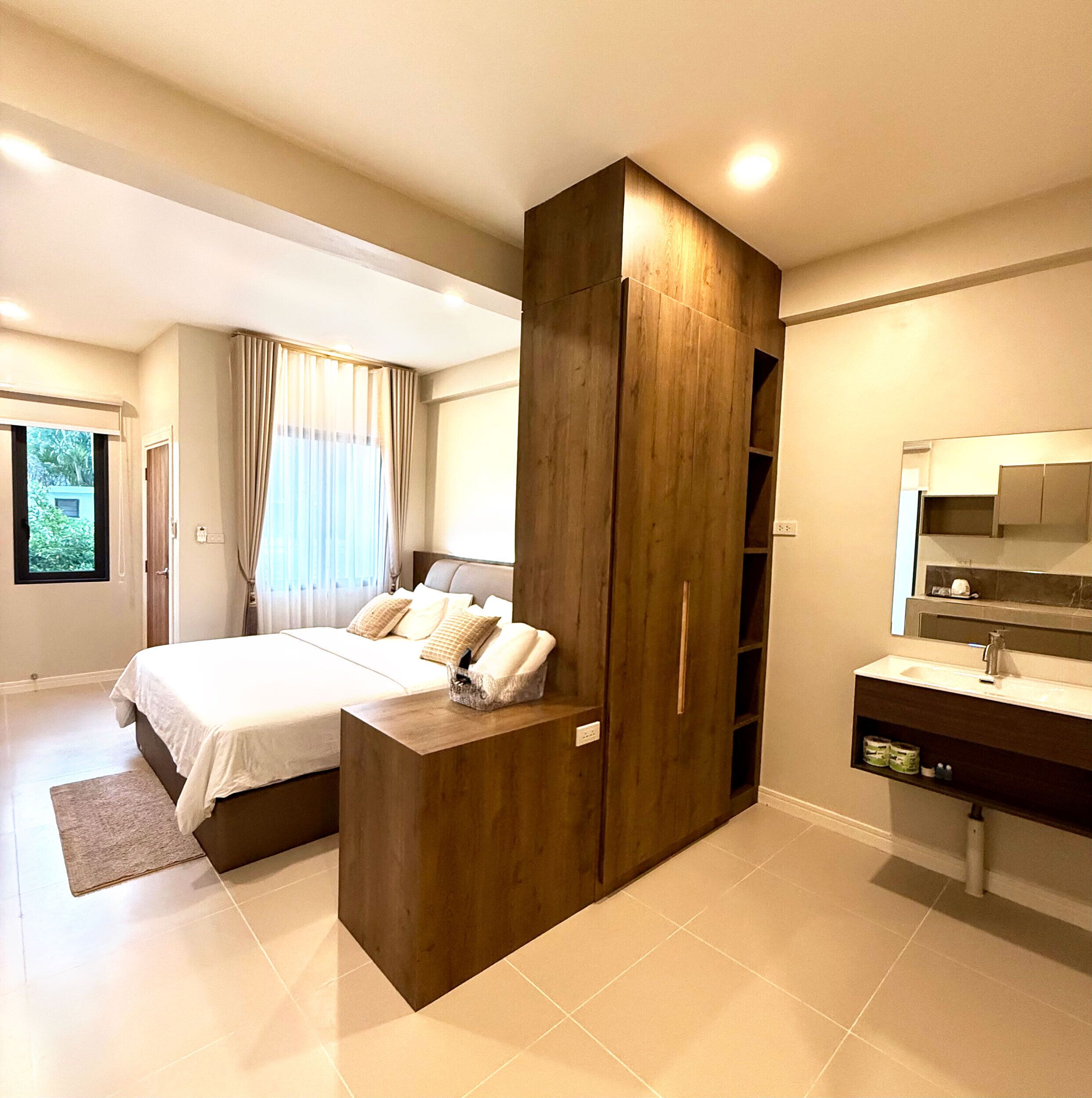 Une chambre moderne avec un grand lit, une armoire intégrée et une salle de bain équipée d’un miroir et d’un lavabo.