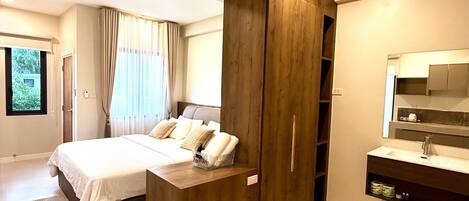 A modern bedroom with a large bed, built-in wardrobe, and a bathroom with a mirror and sink.