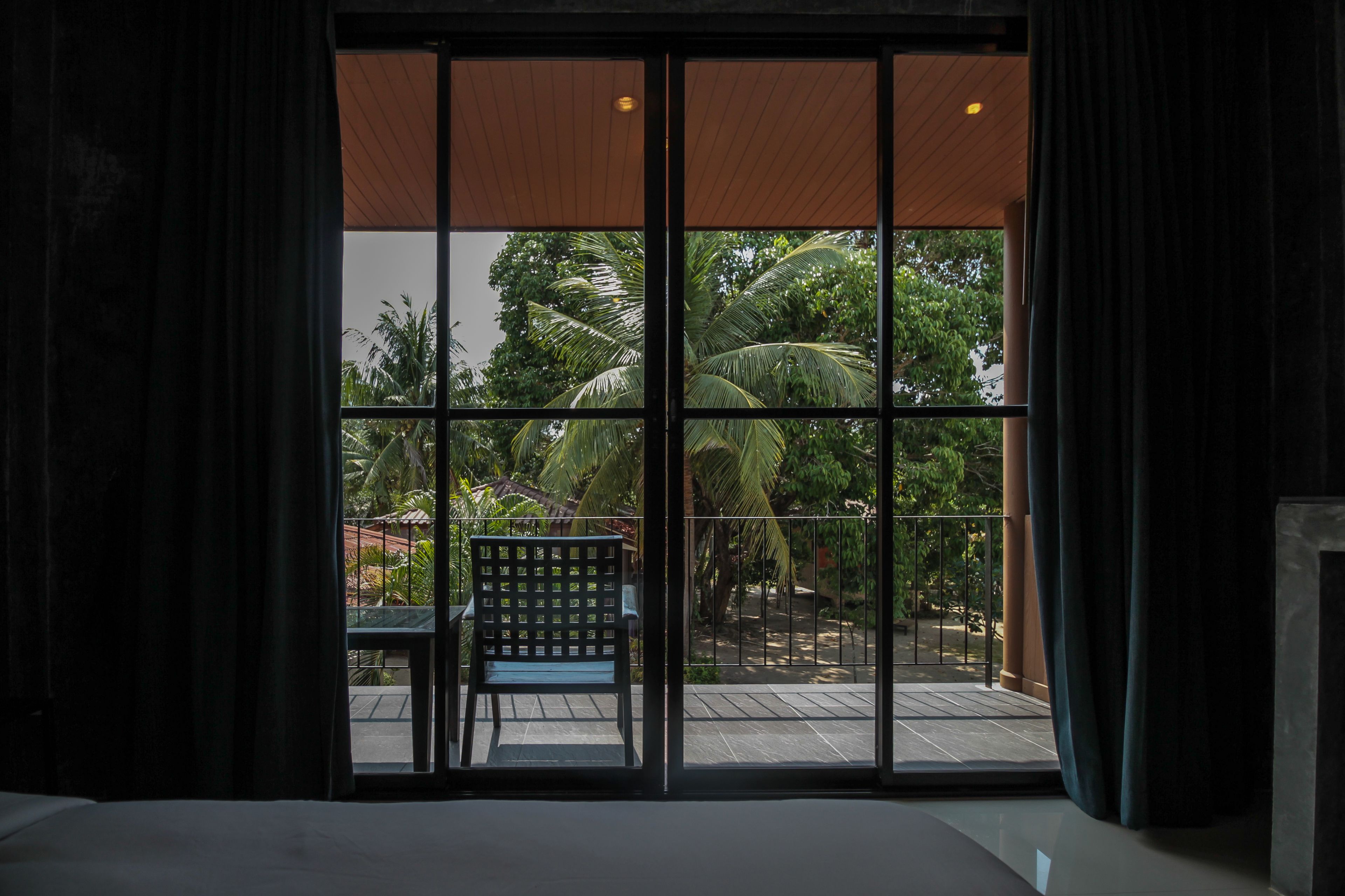 Quarto com uma grande porta de correr de vidro que dá para área externa com cadeira e mesa.