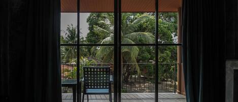 Quarto com uma grande porta de correr de vidro que dá para área externa com cadeira e mesa.