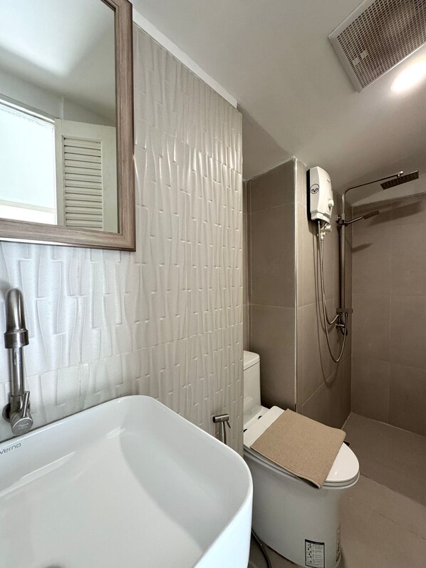 A bathroom with a white bathtub, a toilet, and a shower area.