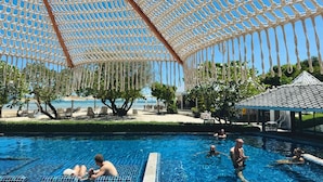 A pool area with a net canopy, lounge chairs, and a view of the beach. - Sabaii Bay Resort (Ko Pha-ngan)