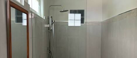 A modern bathroom with a glass-enclosed shower, a white sink, and a large mirror.