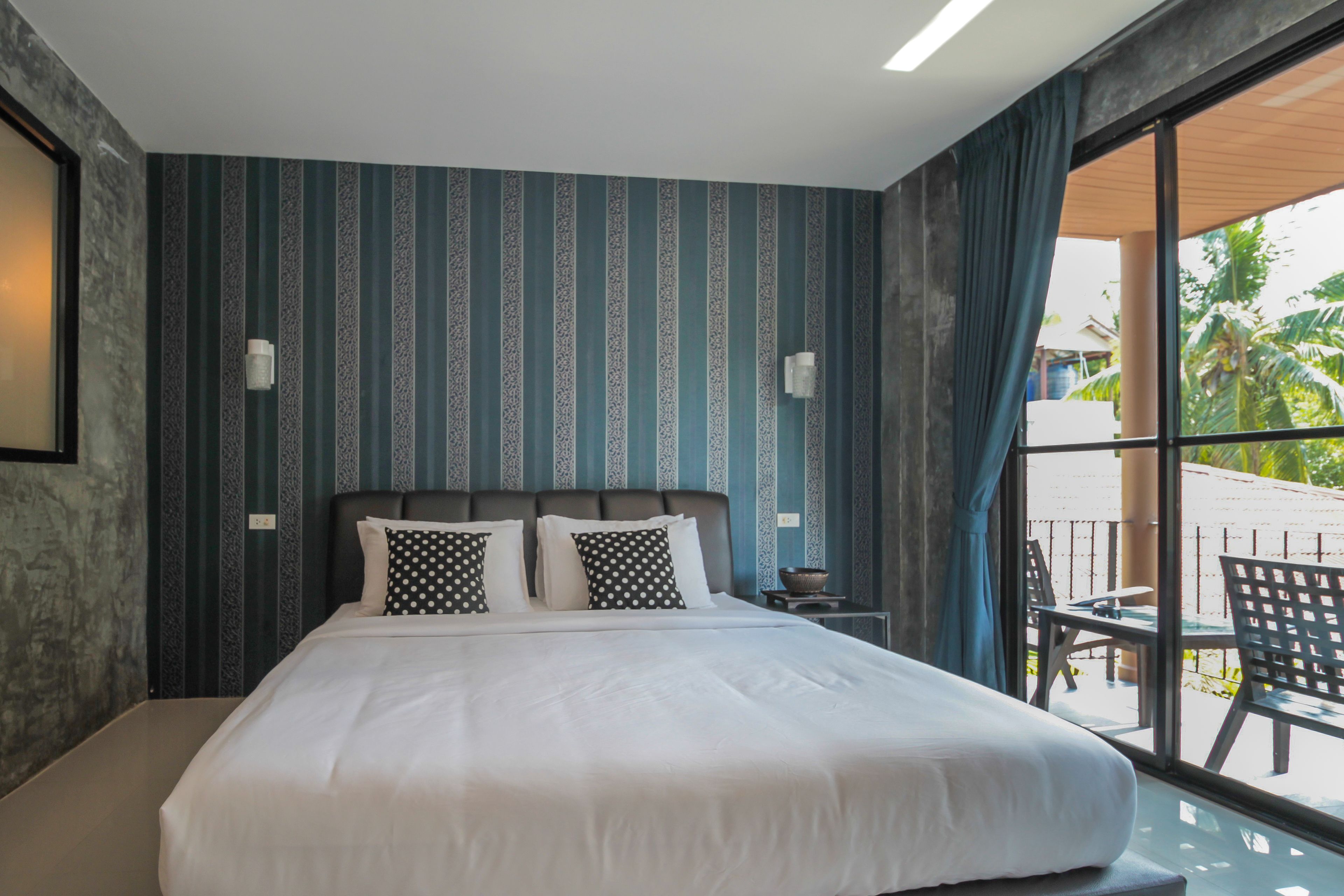 Une chambre d’hôtel moderne avec un grand lit, un papier peint à rayures et une vue sur l’espace extérieur.