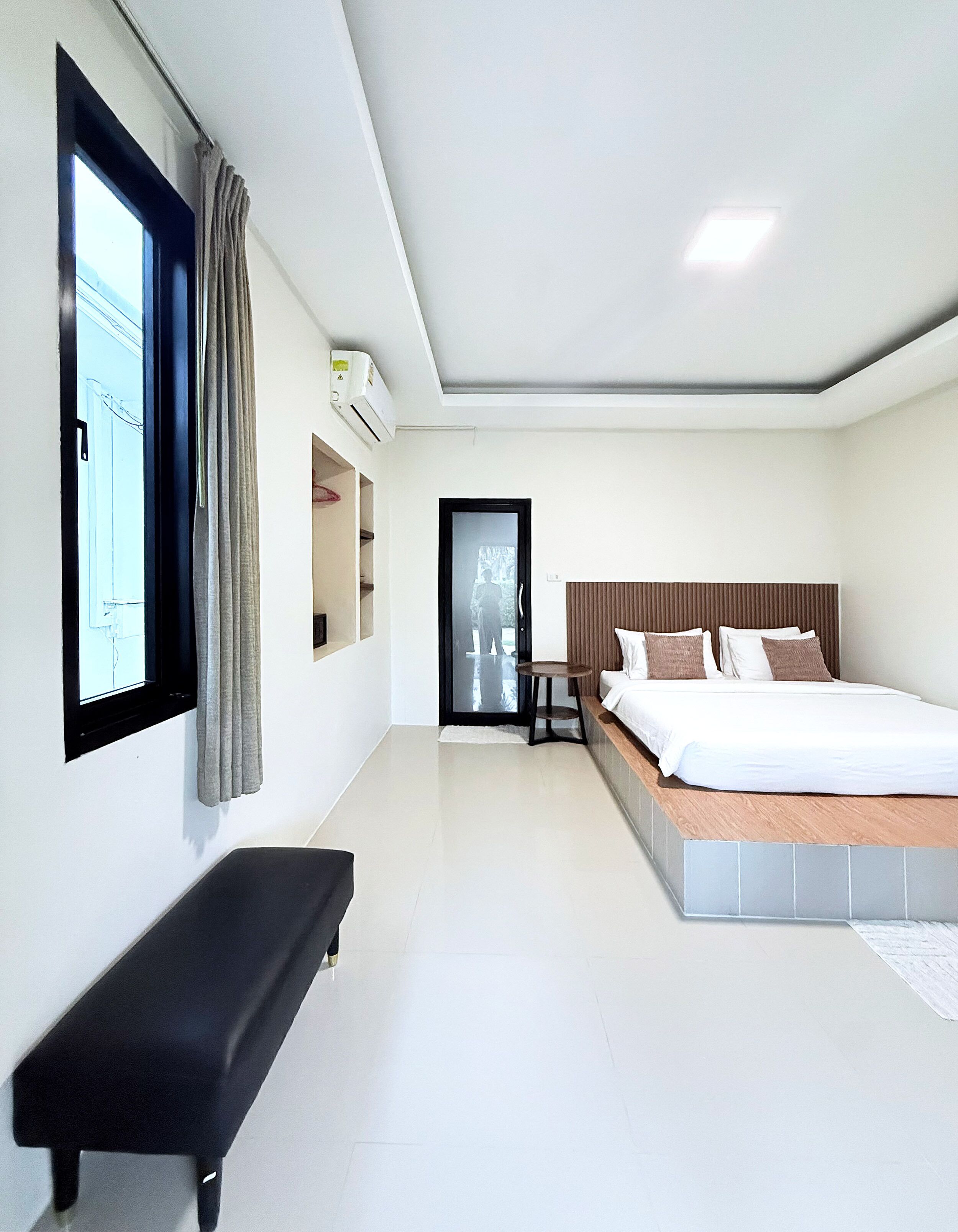 A modern hotel room with a bed, bench, and a small table.
