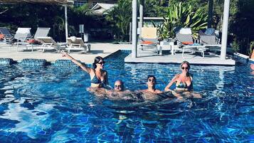 Alberca al aire libre, sombrillas en la alberca y camastros