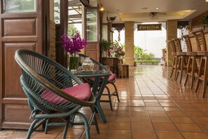 A restaurant with wicker chairs, a table with a vase of flowers, and a sign reading "Korbuah House". - Korbua House (Bangkok)