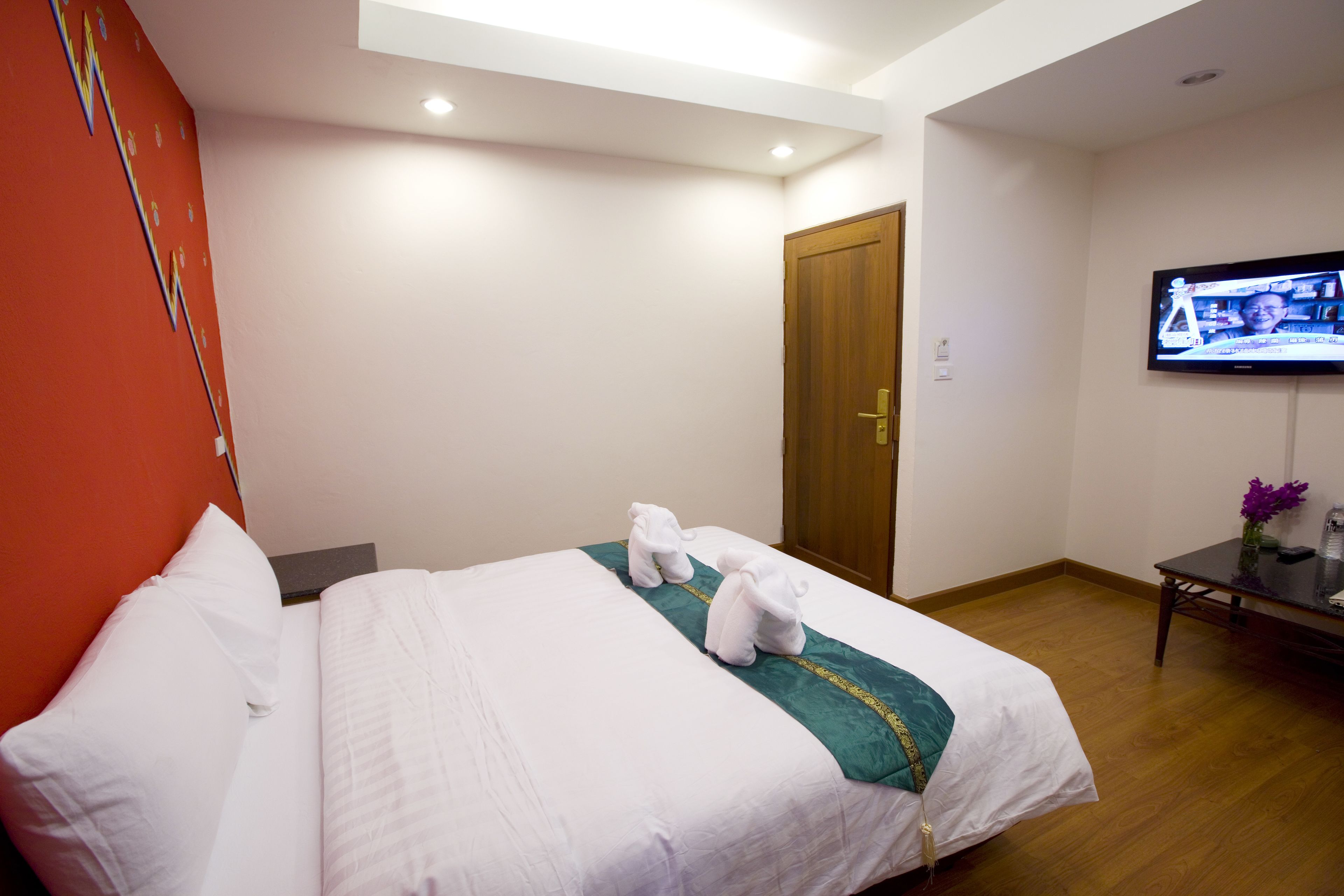 Una habitación de hotel con una cama, un televisor y una puerta de madera.