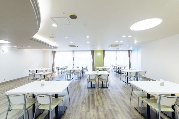 A conference room with multiple tables and chairs, large windows, and a modern ceiling design. - Shin Osaka Hotel (Osaka)