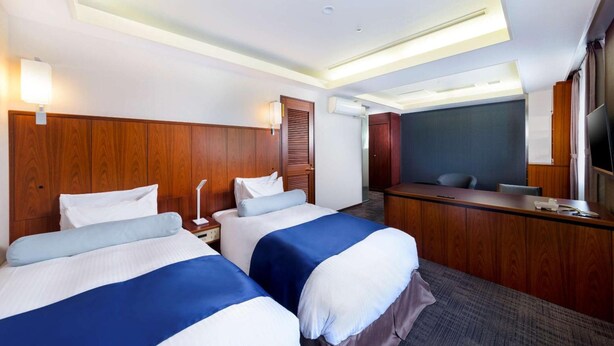 A hotel room with two beds, a desk, a television, and a window. - Shin Osaka Hotel (Osaka)