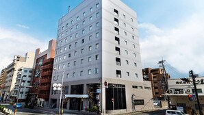 A modern multi-story building with a flat facade, numerous windows, and a visible entrance. - Shin Osaka Hotel (Osaka)