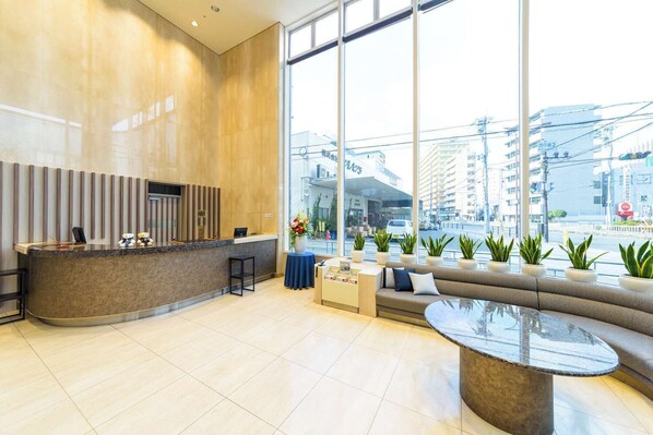 A modern reception area with a curved counter, seating, and large windows offering a city view. - Shin Osaka Hotel (Osaka)
