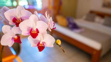 A hotel room with a bed, a small table, and a potted orchid.