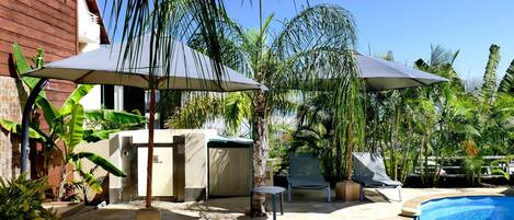 Patio con piscina, mobiliario exterior y sombrillas.