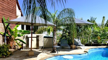 Una piscina al aire libre, sombrillas, sillones reclinables de piscina