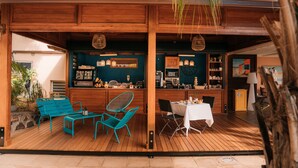 An outdoor dining area with wooden furniture and a bar. - Le Kervéguen (Saint-Paul)