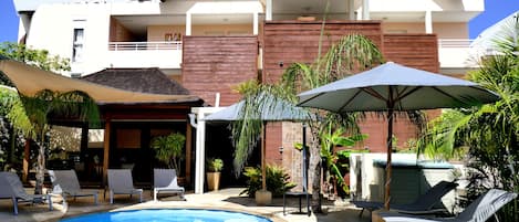 Una piscina al aire libre, sombrillas, sillones reclinables de piscina