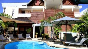 Una piscina al aire libre, sombrillas, sillones reclinables de piscina