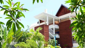 A modern multi-story building with a white facade, wooden accents, and a balcony. - Le Kervéguen (Saint-Paul)