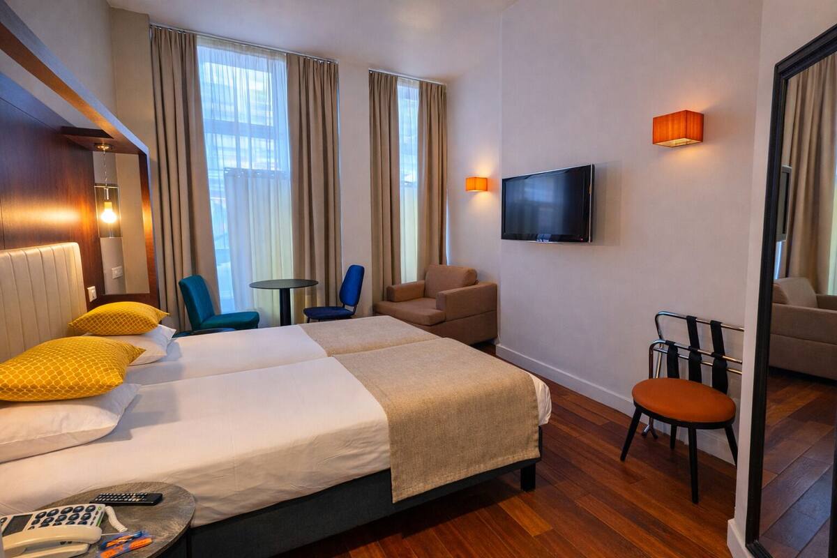 Une chambre d’hôtel avec deux lits, une télévision, un bureau et une chaise.