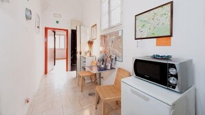 Een smalle gang met een eethoek, een magnetron en een kaart aan de muur.