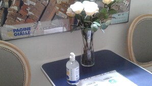 Een tafeltje met een vaas witte rozen, een fles handdesinfecterend middel en een vaccinatieformulier voor COVID-19.