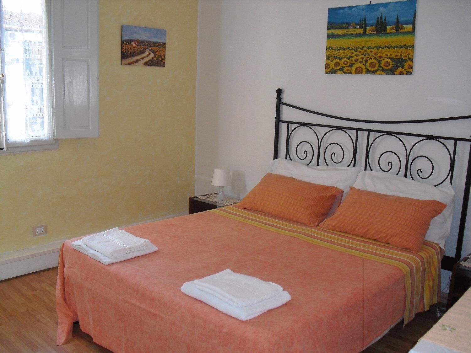 Une chambre à coucher avec un lit, deux oreillers, une table de chevet et un tableau accroché au mur.