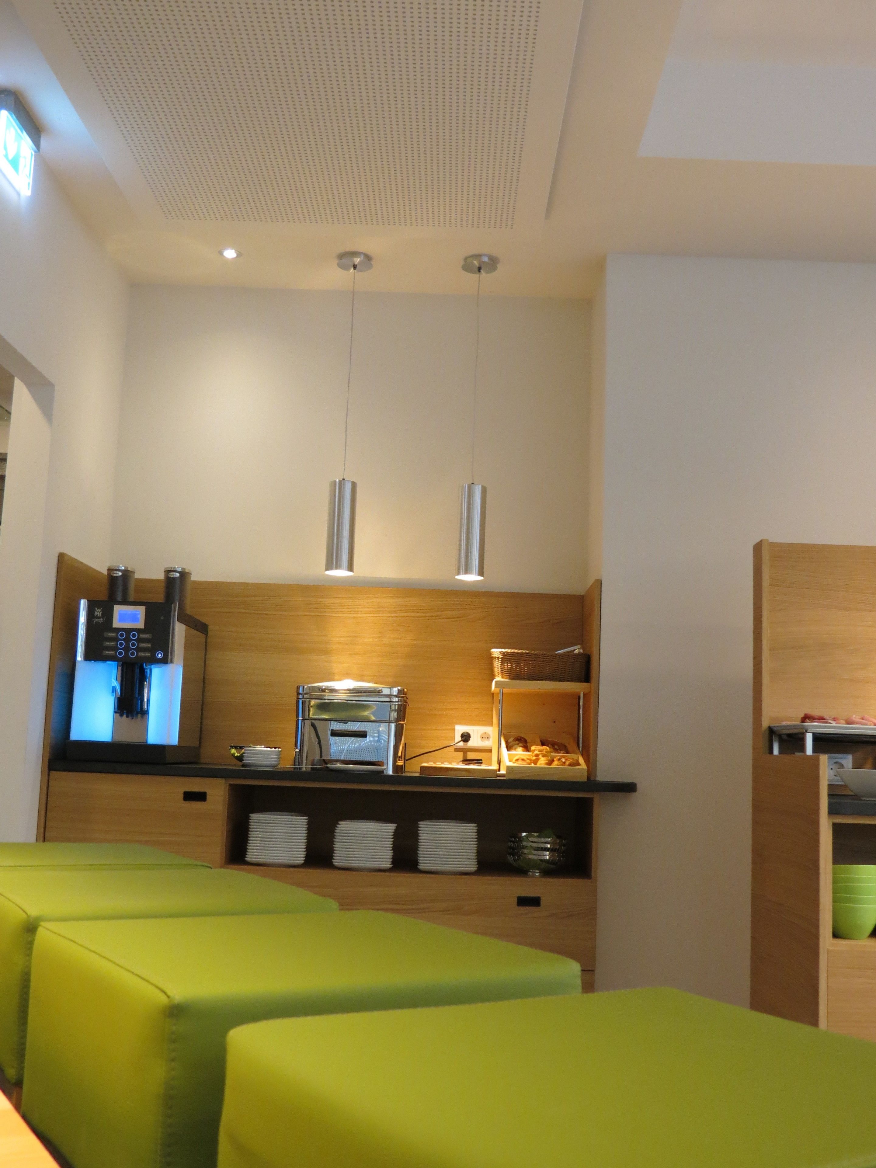 A modern kitchenette with a coffee machine, toaster, and a buffet counter with food items.