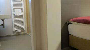 Un baño con inodoro, lavamanos y perchero para toallas.