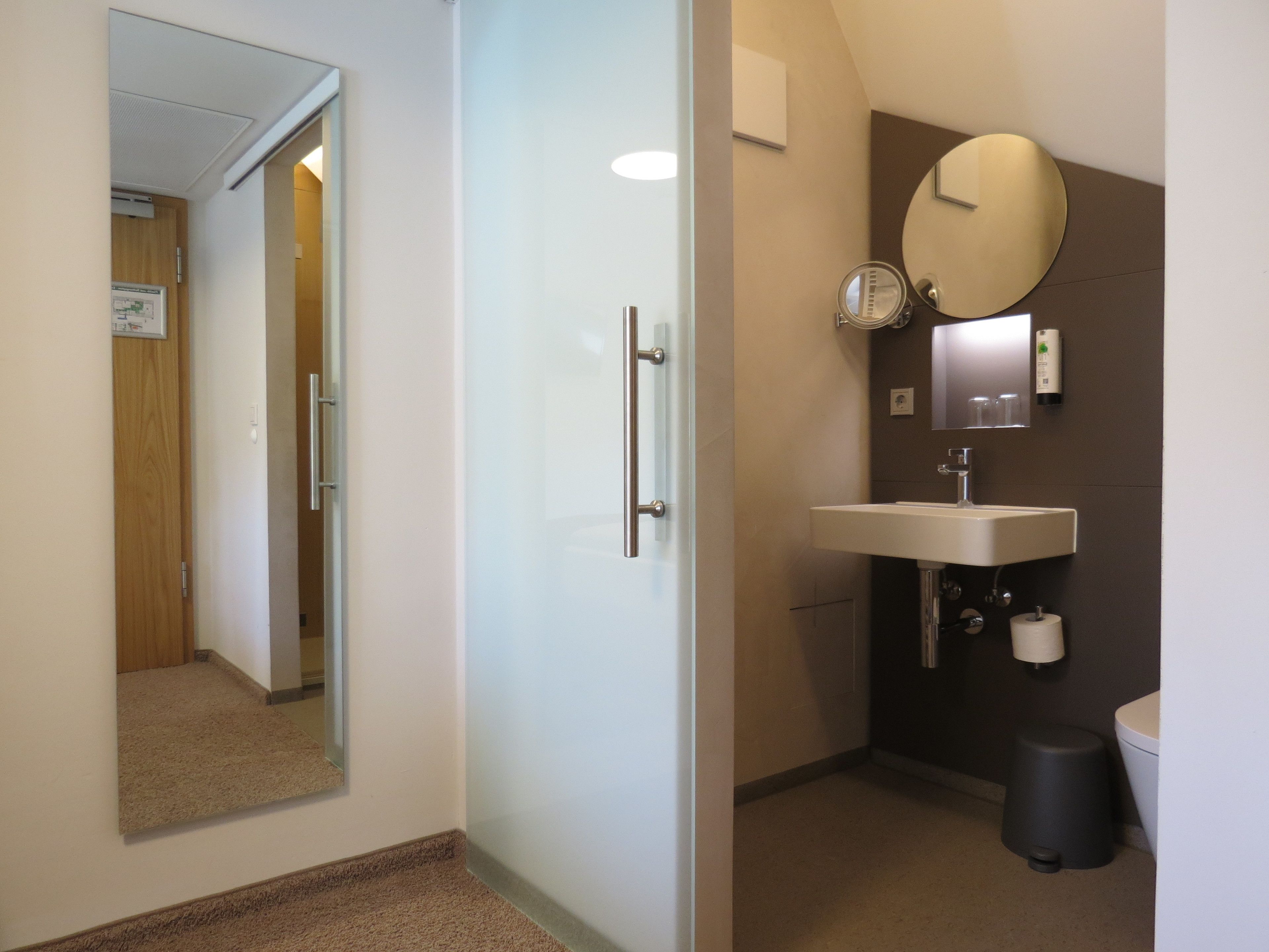 A bathroom with a mirror, sink, and toilet.