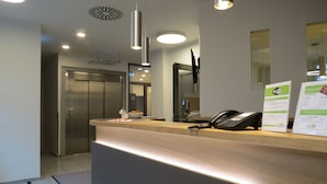 A modern reception desk with a telephone, a bowl of fruit, and a Wi-Fi sign. - Hotel Neuthor (Ulm)