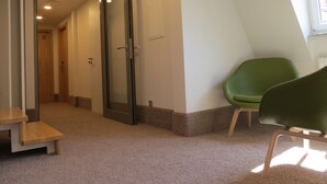 A hallway with a green chair, a wooden bench, and a door marked with the number 33. - Hotel Neuthor (Ulm)