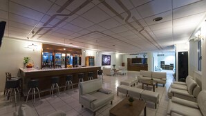 A spacious living area with a bar, sofas, and a television. - Galaxy Hotel (Ierapetra)