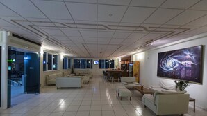 A spacious lobby with a high ceiling, multiple seating areas, and a large wall-mounted artwork. - Galaxy Hotel (Ierapetra)